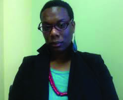 Headshot photo of Tiffany Jeanette King wearing glasses, a black jacket, red neckless
